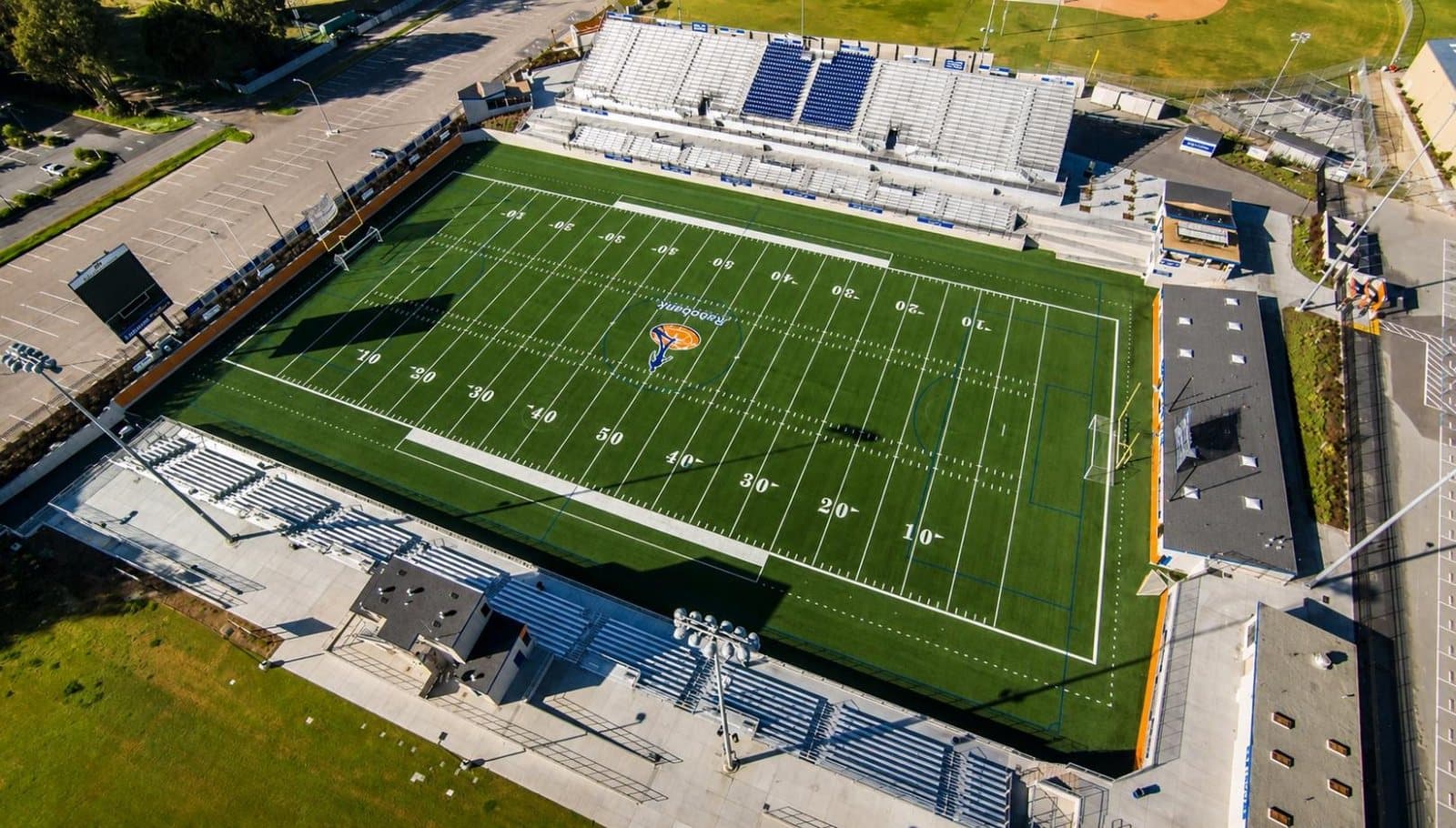 Aerial view of Rabobank Stadium, showing the marked green playing field with covered grandstand seating along one side and open bleachers opposite.